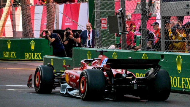 Ferrari's Monegasque driver Charles Leclerc crosses first the finish line as Paris Saint-Germain's French forward Kylian Mbappe waves the checkered flag at the end of the Formula One Monaco Grand Prix on May 26, 2024 at the Circuit de Monaco. (Photo by ANDREJ ISAKOVIC / AFP)