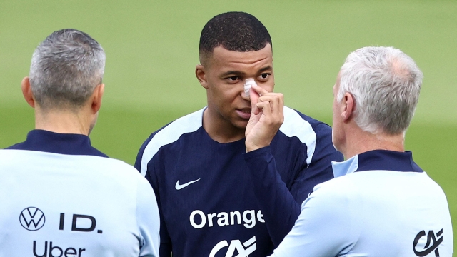 France's forward #10 Kylian Mbappe (C), who broke his nose during his country's opening win against Austria, speaks with France's head coach Didier Deschamps (R) during a training session within the UEFA Euro 2024 Football Championship, at the Home Deluxe Arena Stadium in Paderborn, western Germany, on June 19, 2024. Mbappe underwent tests at a hospital in Duesseldorf before rejoining the France squad at their base in Paderborn. (Photo by FRANCK FIFE / AFP)