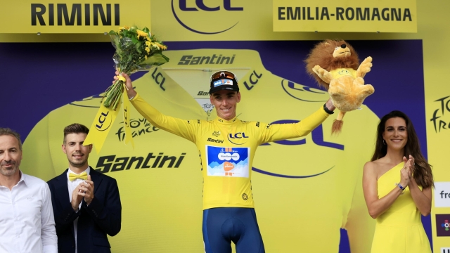 epa11445350 French rider Romain Bardet of Team DSM celebrates on the podium wearing the overall leader's yellow jersey after winning the first stage of the 2024 Tour de France cycling race over 206km from Florence to Rimini, Italy, 29 June 2024.  EPA/GUILLAUME HORCAJUELO