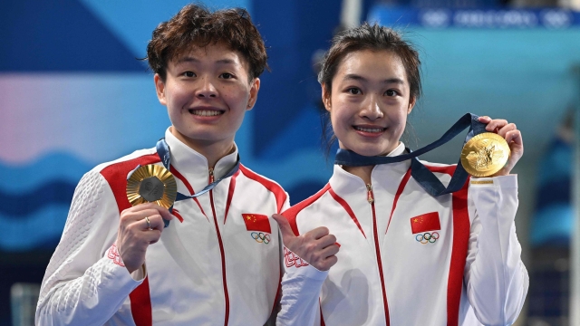 Gold medallists China's Chang Yani and Chen Yiwen pose with their medals after the women's synchronised 3m springboard diving final at the Paris 2024 Olympic Games at the Aquatics Centre in Saint-Denis, north of Paris, on July 27, 2024. (Photo by SEBASTIEN BOZON / AFP)