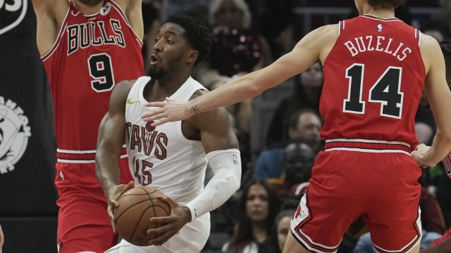 Cleveland Cavaliers guard Donovan Mitchell (45) drives between Chicago Bulls' Nikola Vucevic (9) and forward Matas Buzelis (14) in the first half of a preseason NBA basketball game, Tuesday, Oct. 8, 2024, in Cleveland. (AP Photo/Sue Ogrocki)