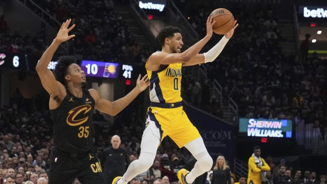 Indiana Pacers guard Tyrese Haliburton, right, passes the ball as Cleveland Cavaliers forward Isaac Okoro defends during the first half in Game 5 of an Eastern Conference semifinal NBA basketball playoff Tuesday, May 13, 2025, in Cleveland. (AP Photo/Sue Ogrocki)