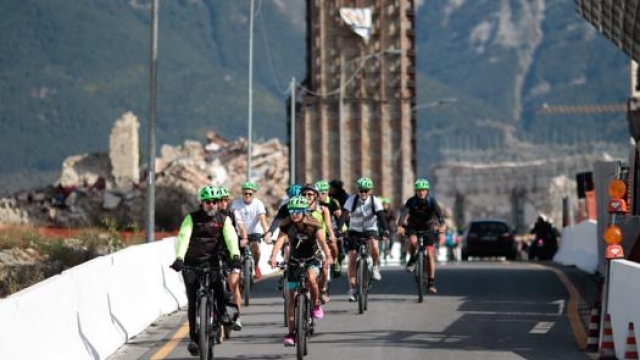 Un momento della pedalata solidale Bosch nelle terre terremotate del Centro Italia: alle spalle dei bikers, uno scorcio di Amatrice