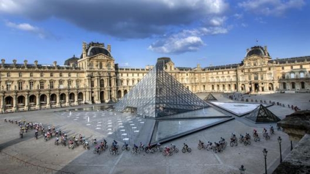 Il passaggio del Tour de France davanti all’ingresso del Louvre. Afp
