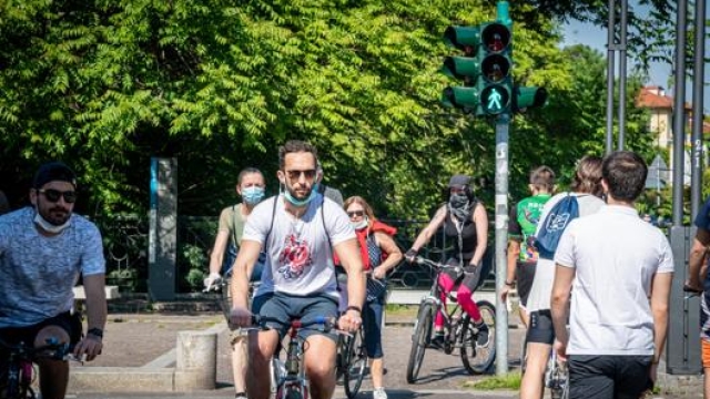 Persone in bicicletta a Milano lungo il naviglio della Martesana. Ansa