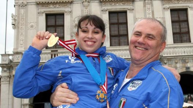 2006: Vanessa Ferrari, campionessa del mondo di ginnastica, mostra le sue medaglie mentre posa con l'allenatore Enrico Casella .