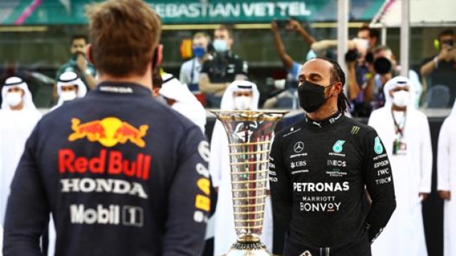 Lewis Hamilton davanti al trofeo iridato e a Max Verstappen ad Abu Dhabi. Getty