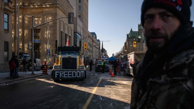 TOPSHOT - A demonstrator watches as a driver relocates his vehicle onto the central Wellington street area, during a protest by truck drivers over pandemic health rules and the Trudeau government, outside the parliament of Canada in Ottawa on February 14, 2022. (Photo by Ed JONES / AFP)