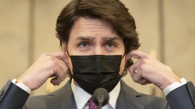 Canadian Prime Minister Justin Trudeau removes his mask as he arrives at a news conference to announce the Emergencies Act will be invoked to deal with protests, Monday, Feb. 14, 2022 in Ottawa. Trudeau says he has invoked the act to bring to an end antigovernment blockades he describes as illegal. (Adrian Wyld/The Canadian Press via AP)