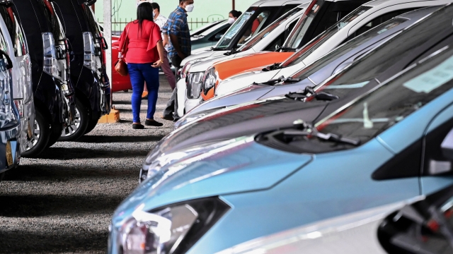 In this picture taken on January 10, 2022, customers look at cars displayed for sale at a car dealership in Malabe, in the district of Colombo. - Supermarket shelves are bare and restaurants can't serve meals, but Sri Lanka's economic crisis is a bonanza for used car dealers, with vehicle shortages pushing prices higher than a house in a nice area. (Photo by ISHARA S. KODIKARA / AFP) / TO GO WITH SriLanka-economy-transport-auto,FOCUS
