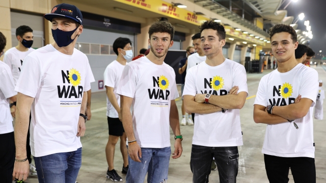 BAHRAIN, BAHRAIN - MARCH 09: Max Verstappen of the Netherlands and Oracle Red Bull Racing, Pierre Gasly of France and Scuderia AlphaTauri, Charles Leclerc of Monaco and Ferrari and Lando Norris of Great Britain and McLaren talk while wearing t-shirts promoting peace and sympathy with Ukraine prior to F1 Testing at Bahrain International Circuit on March 09, 2022 in Bahrain, Bahrain. (Photo by Mark Thompson/Getty Images)