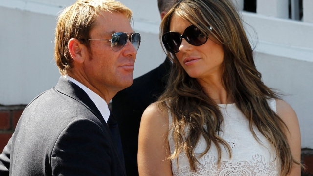 (FILES) In this file photograph taken on July 19, 2013, Australian former cricketer Shane Warne (L) with his fiancee British actress and model Liz Hurley are seen together after he is presented with an award during the tea interval on the second day of the second Ashes cricket test match between England and Australia at Lord's cricket ground in north London. - Australia cricket great Shane Warne, widely regarded as the greatest leg-spinner of all time, has died aged 52 according to a statement issued by his management company on March 4, 2022. Warne's management said he died in Koh Samui, Thailand, of a suspected heart attack. (Photo by Ian KINGTON / AFP)