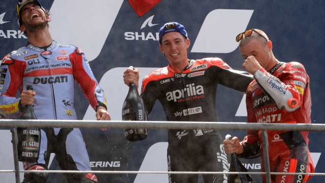 Second placed Ducati Lenovo Australian rider Jack Miller (R), first placed Gresini Racing Italian rider Enea Bastianini (L), and third placed Aprilia Spanish rider Aleix Espargaro (R) celebrate with champagne on the podium after the French Moto GP Grand Prix, at the Bugatti circuit in Le Mans, northwestern France, on May 15, 2022. (Photo by JEAN-FRANCOIS MONIER / AFP)