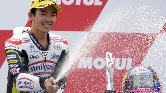 Japan's rider Ayumu Sasaki of the Sterilgarda Husqvarna Max sprays champagne to celebrate his victory in the Moto3 race at the Dutch Grand Prix in Assen, northern Netherlands, Sunday, June 26, 2022. (AP Photo/Peter Dejong)