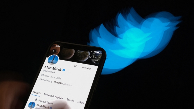This illustration photo taken on July 8, 2022 shows Elon Musk's Twitter page displayed on the screen of a smartphone with Twitter logo in the background in Los Angeles. - Elon Musk pulled the plug on his deal to buy Twitter on July 8, 2022, accusing the company of "misleading" statements about the number of fake accounts, a regulatory filing showed. (Photo by Chris DELMAS / AFP)
