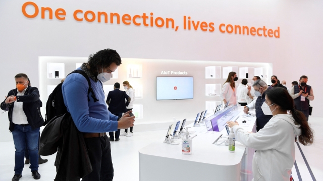 Visitors look at phones on Xiaomi's stand on the opening day of the MWC (Mobile World Congress) in Barcelona on February 28, 2022. - The world's biggest mobile fair is held from February 28 to March 3, 2022. (Photo by Josep LAGO / AFP)