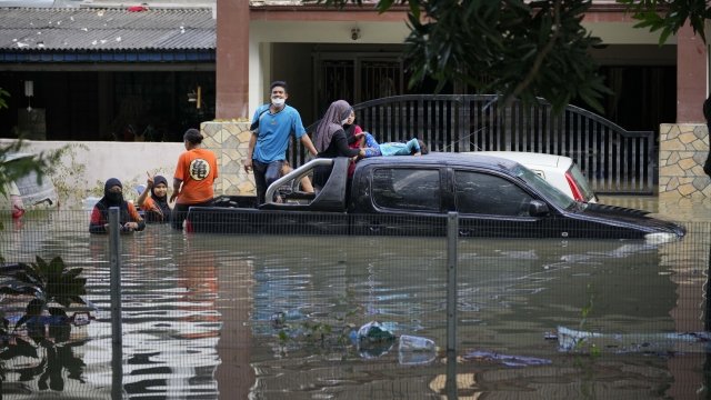 Residents are trapped at their house as a road was flooded in Shah Alam, on the outskirts of Kuala Lumpur, Malaysia, Monday, Dec. 20, 2021. Rescue services on Monday worked to free thousands of people trapped by Malaysia's worst flooding in years after heavy rains stopped following more than three days of torrential downpours in the capital and around the country. (AP Photo/Vincent Thian)
