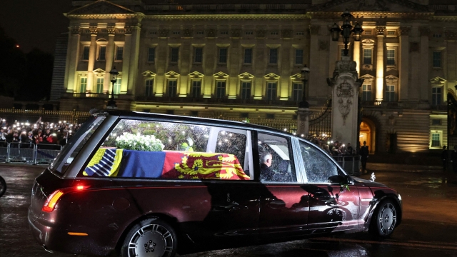 TOPSHOT - The coffin of Queen Elizabeth II arrives in the Royal Hearse at Buckingham Palace in London on September 13, 2022, where it will rest in the Palace's Bow Room overnight. - Queen Elizabeth II's coffin will on Tuesday be flown by the Royal Air Force from Edinburgh to London, accompanied by the queen's only daughter Anne, the Princess Royal, and driven to Buckingham Palace, to rest in the Bow Room. (Photo by PAUL CHILDS / POOL / AFP)