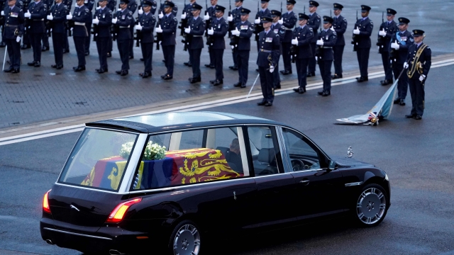 TOPSHOT - The Queen's Colour Squadron, RAF, stand by as the coffin of Queen Elizabeth II is taken away in the Royal Hearse from the Royal Air Force Northolt airbase on September 13, 2022, to travel to Buckingham Palace. - Mourners in Edinburgh filed past the coffin of Queen Elizabeth II through the night, before the monarch's coffin returns to London to Lie in State ahead of her funeral on September 19. (Photo by Andrew Matthews / POOL / AFP)