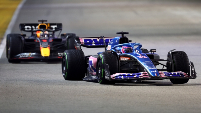 SINGAPORE, SINGAPORE - OCTOBER 02: Fernando Alonso of Spain driving the (14) Alpine F1 A522 Renault leads Max Verstappen of the Netherlands driving the (1) Oracle Red Bull Racing RB18 during the F1 Grand Prix of Singapore at Marina Bay Street Circuit on October 02, 2022 in Singapore, Singapore. (Photo by Clive Rose/Getty Images,)