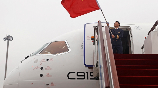 Zhao Hongbing, the caption of a Commercial Aircraft Corp of China (COMAC) C919 aircraft, China's first domestically produced large passenger jet, waves a national flag after landing at Hongqiao International Airport as it is formally handed over to China Eastern Airlines in Shanghai on December 9, 2022. (Photo by AFP) / China OUT