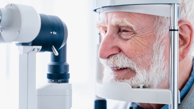 Cropped photo of happy senior patient being diagnosed with ophthalmic equipment