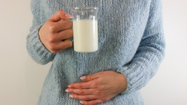 Woman with stomach ache holding glass of milk. Dairy, lactose intolerance, allergy concept