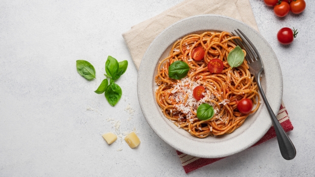 Spaghetti pasta with tomato sauce, basil and cheese in plate on light background, top view