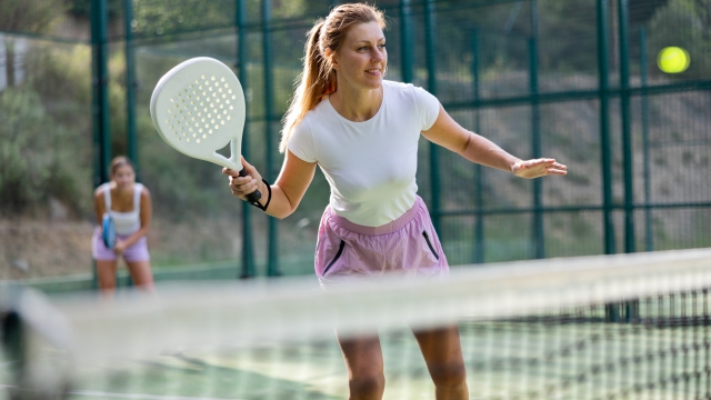 Padel game - woman with partners plays on the tennis court