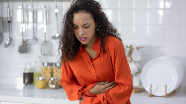 stomach disease, young woman with stomach ache, having food poisoning in kitchen