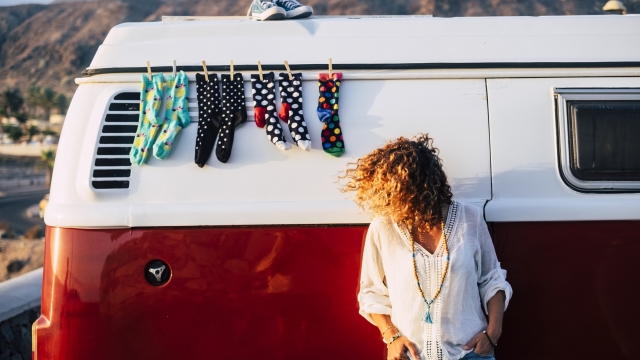 Trendy fashion young woman people outside a cozy and beautiful vintage retro van with socks and shoes - perfect vanlife travel lifestyle female enjoying the outdoor and the independence