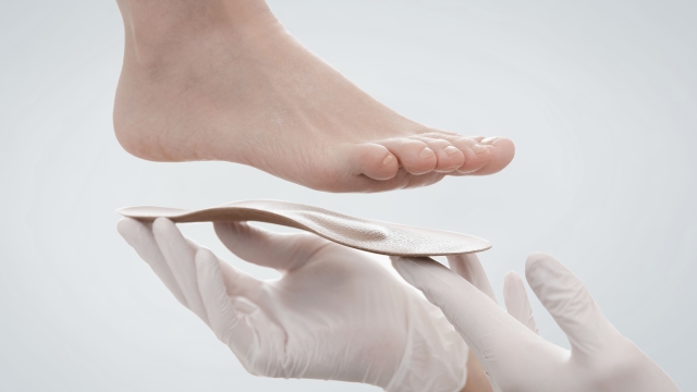 Orthopedic insole isolated on a white background. Hands in rubber gloves hold an orthopedic insole. Foot care, comfort for the feet. Doctor orthopedist tests the medical device. Flat feet correction.