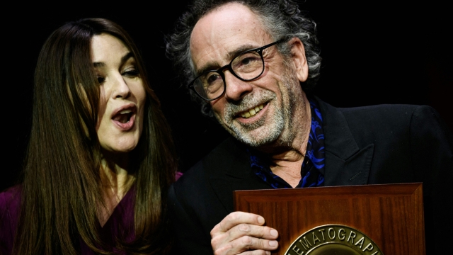 US director Tim Burton (R) receives the Lumiere Award from Italian actress Monica Bellucci during the award ceremony of the 14th edition of the Lumiere Film Festival in Lyon, central-eastern France, on October 21, 2022. (Photo by JEFF PACHOUD / AFP)