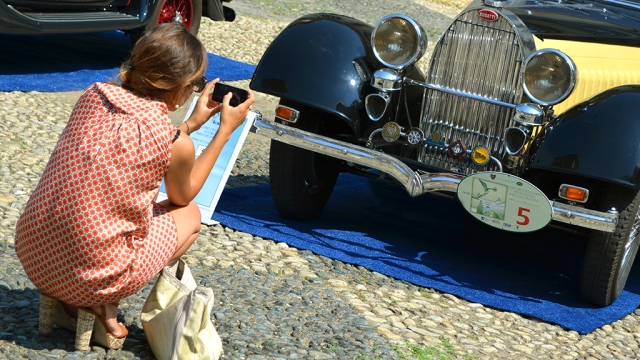 Una turista fotografa una Bugatti ad un raduno Asi