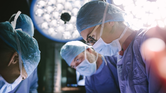 Concentrated female surgeon performing surgery with her team in hospital operating room. Medics during surgery in operation theater.