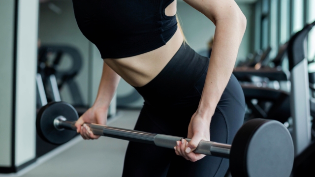 A young girl in black sportswear is engaged in the gym with dumbbells. Fitness club concept