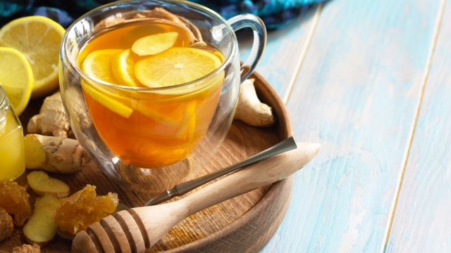 Cup of hot tea with lemon, ginger, honeycomb and honey on a wooden table. Copy space.