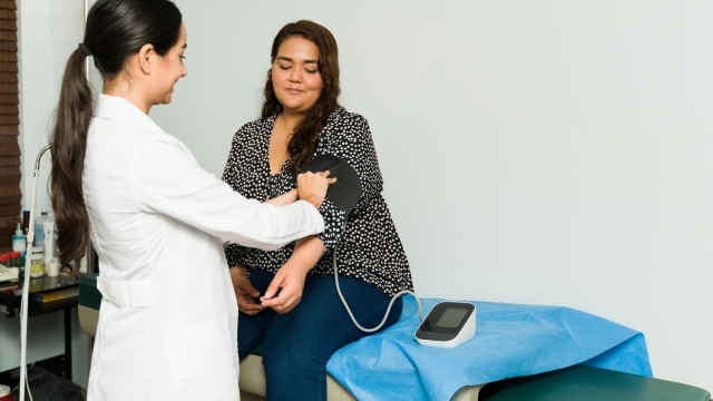 Happy female cardiologist checking the blood pressure of a sick female patient for a medical examination