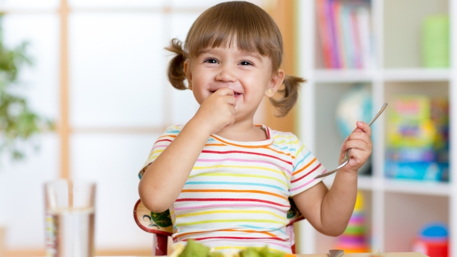 Funny kid girl eating healthy food in kindergarten