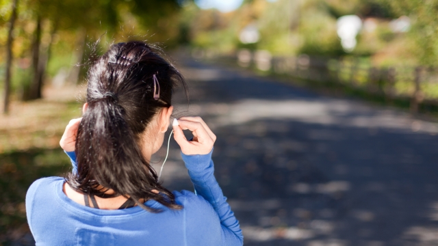 Rear view, close-up of a woman with earbuds.