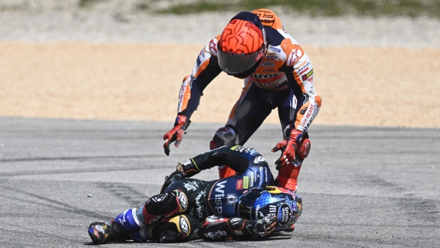 Honda Spanish rider Marc Marquez (R) checks on Aprilia Portuguese rider Miguel Oliveira after crashing during the MotoGP race of the Portuguese Grand Prix at the Algarve International Circuit in Portimao, on March 26, 2023. (Photo by PATRICIA DE MELO MOREIRA / AFP)