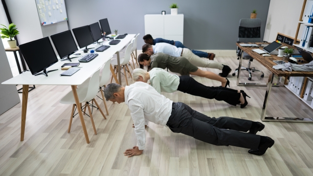 Group Of People Doing Pushups Exercise At Workplace