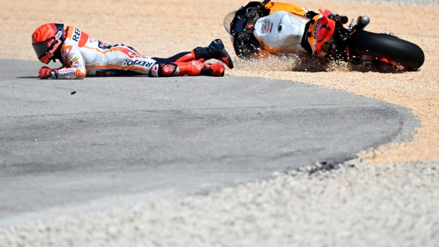 TOPSHOT - Honda Spanish rider Marc Marquez falls after crashing with Aprilia Portuguese rider Miguel Oliveira (out of frame) during the MotoGP race of the Portuguese Grand Prix at the Algarve International Circuit in Portimao, on March 26, 2023. (Photo by PATRICIA DE MELO MOREIRA / AFP)