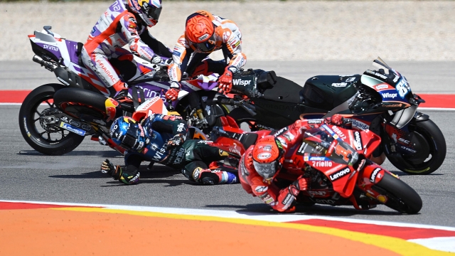 Honda Spanish rider Marc Marquez (C TOP) crashes with Aprilia Portuguese rider Miguel Oliveira (C BOTTOM) as Ducati Italian rider Francesco Bagnaia (R) rides past during the MotoGP race of the Portuguese Grand Prix at the Algarve International Circuit in Portimao, on March 26, 2023. (Photo by PATRICIA DE MELO MOREIRA / AFP)