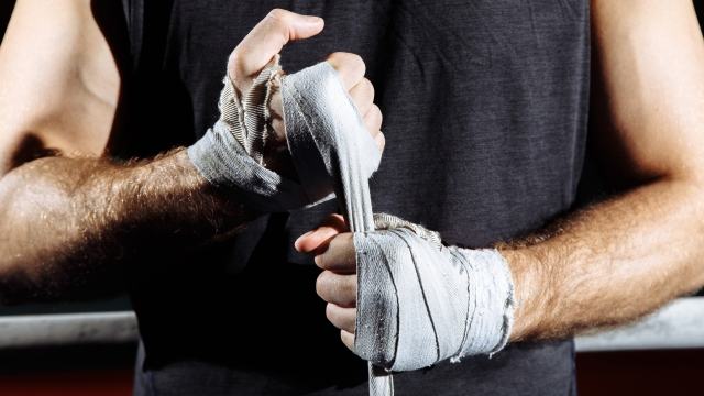 Strong man wrap hands on black background. Man is wrapping hands with boxing wraps, ready for training and active exercise