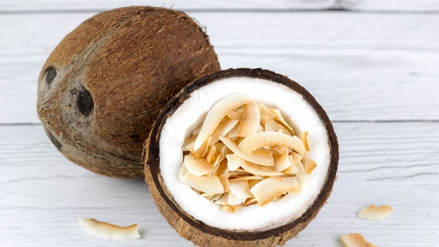 Coconut chips or coconut flakes in fresh coconut on a wooden background. Healthy snacks. Coconut dessert.