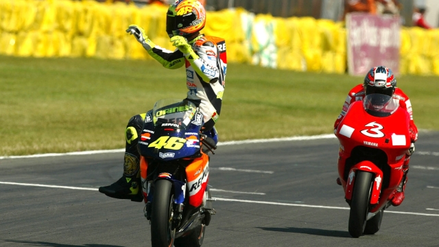 Valentino Rossi rides his Honda sideways as he crosses the finish line to win of the British Motorcycle Grand Prix, with Max Biaggi No 3, who finished second at Donington Park,  England Sunday July 14, 2002. (AP Photo/Alastair Grant)