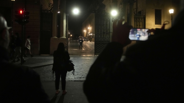 Reporters film the Santa Anna gate at the Vatican, late Thursday, May 18, 2023. A car driven by someone with apparent psychiatric problems rushed through Santa Anna gate Thursday evening and sped past Swiss Guards into a palace courtyard before the driver was apprehended by police. Vatican gendarmes fired a shot at the speeding car's front tires after it rushed the gate, but the vehicle managed to continue on its way, the Vatican press office said in a statement late Thursday. (AP Photo/Andrew Medichini)
