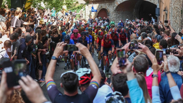 TOPSHOT - Spectators cheer as the poack of riuders cycles in the ascent of the Bergamo Alta during the fifteenth stage of the Giro d'Italia 2023 cycling race, 195 km between Seregno and Bergamo, on May 21, 2023. (Photo by Luca Bettini / AFP)