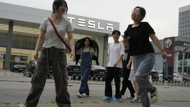 Young Chinese walk past a Tesla showroom in Beijing, Tuesday, May 30, 2023. China?s foreign minister met Tesla Ltd. CEO Elon Musk on Tuesday and said strained U.S.-Chinese relations require ?mutual respect,? while delivering a message of reassurance that foreign companies are welcome. (AP Photo/Ng Han Guan)